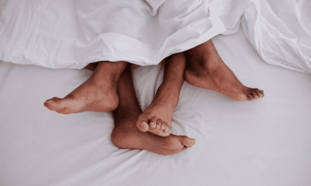 two pairs of feet sticking out of a bedsheet