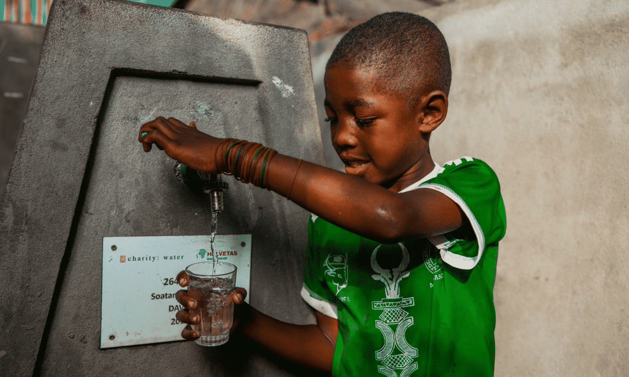 a young boy filling up a glass of water