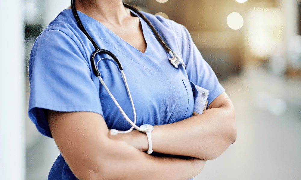 der Torso einer Krankenschwester, die einen Kittel und ein Stethoskop trägt und die Arme verschränkt