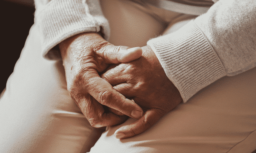 eine ältere Frau hat die Hände im Schoß gefaltet