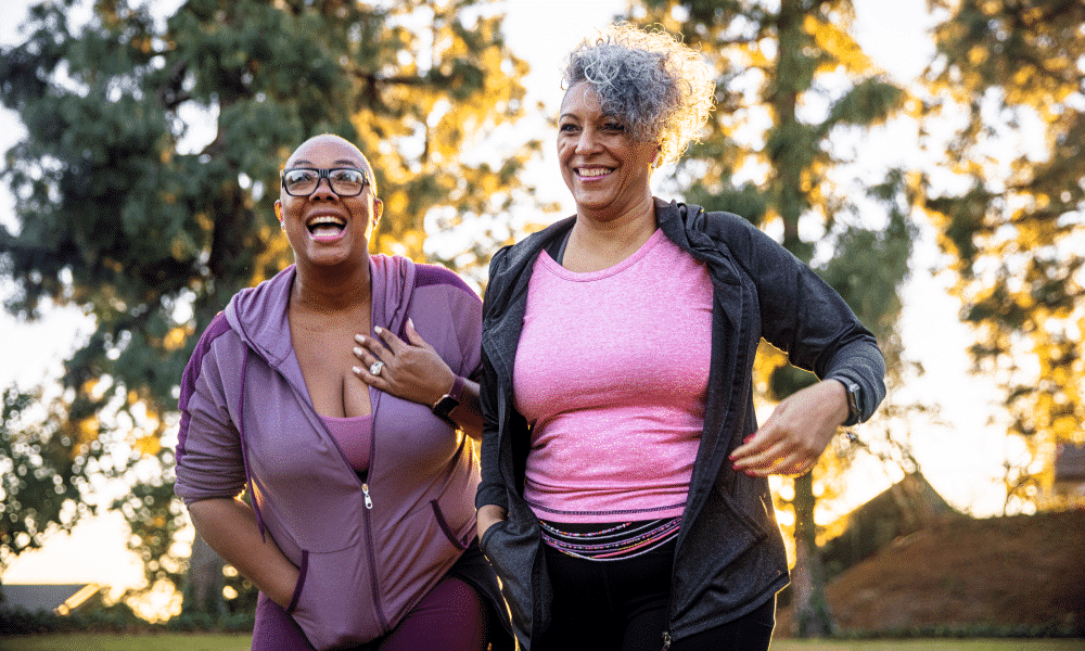 two middle aged women walking in the park together and laughing