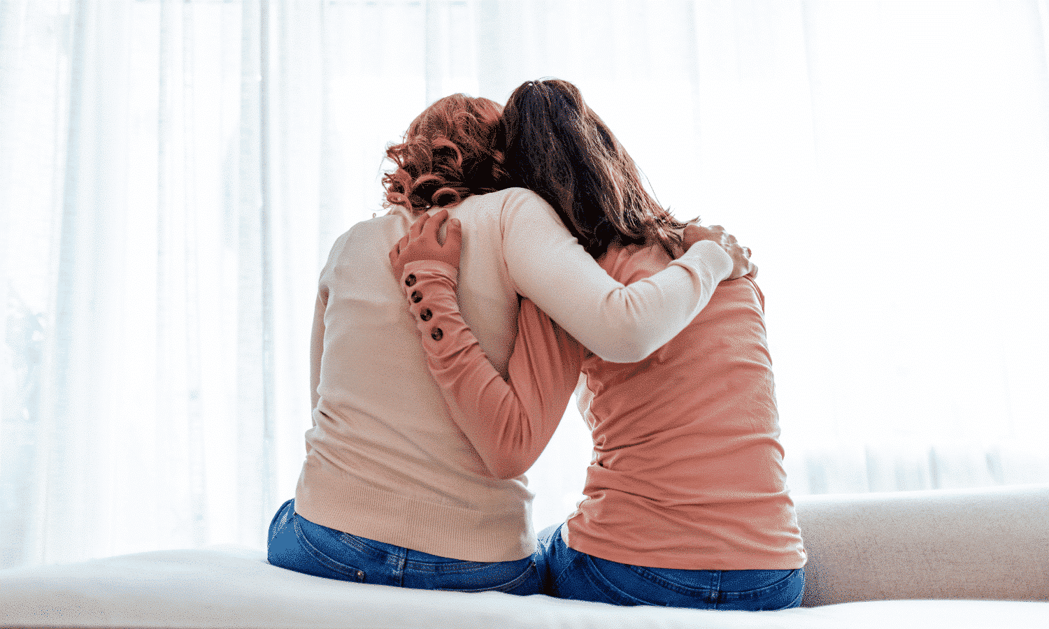 two women sitting on a couch with their arms around each other