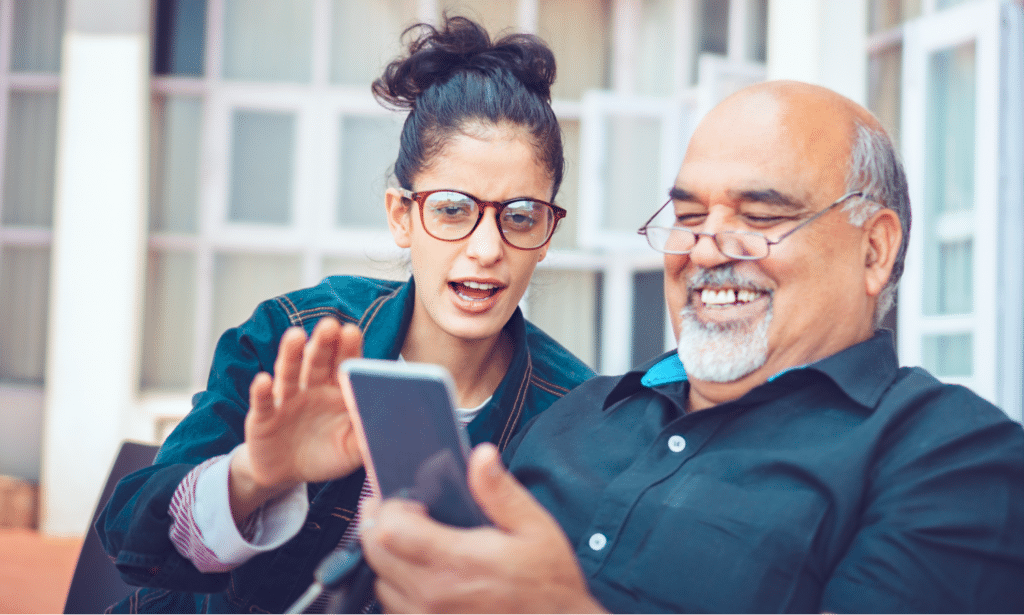 an older man and younger woman looking at a smartphone together