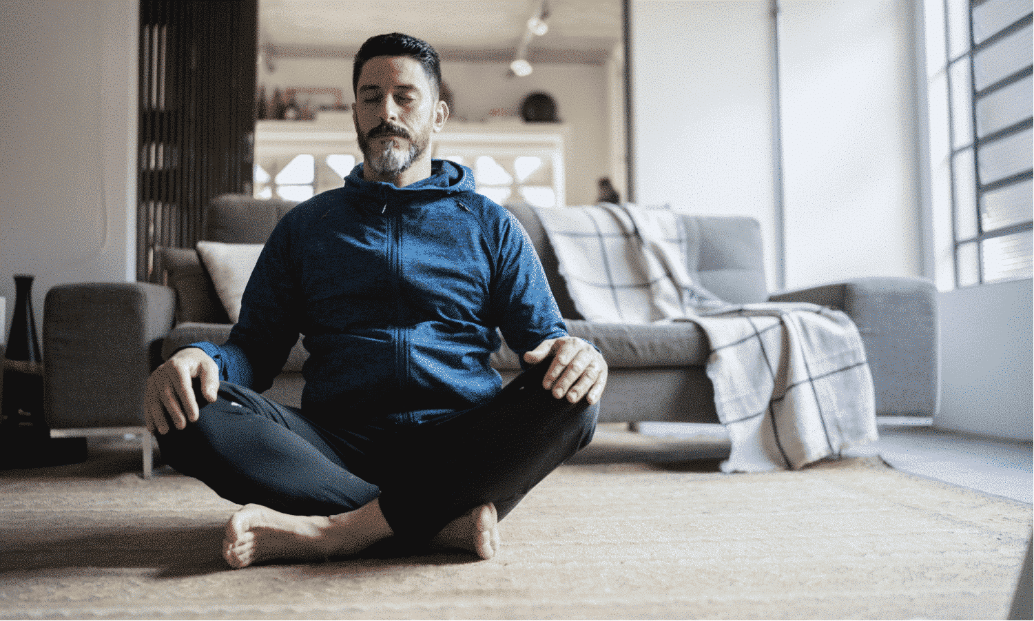 un homme d'âge moyen assis sur le sol en train de méditer